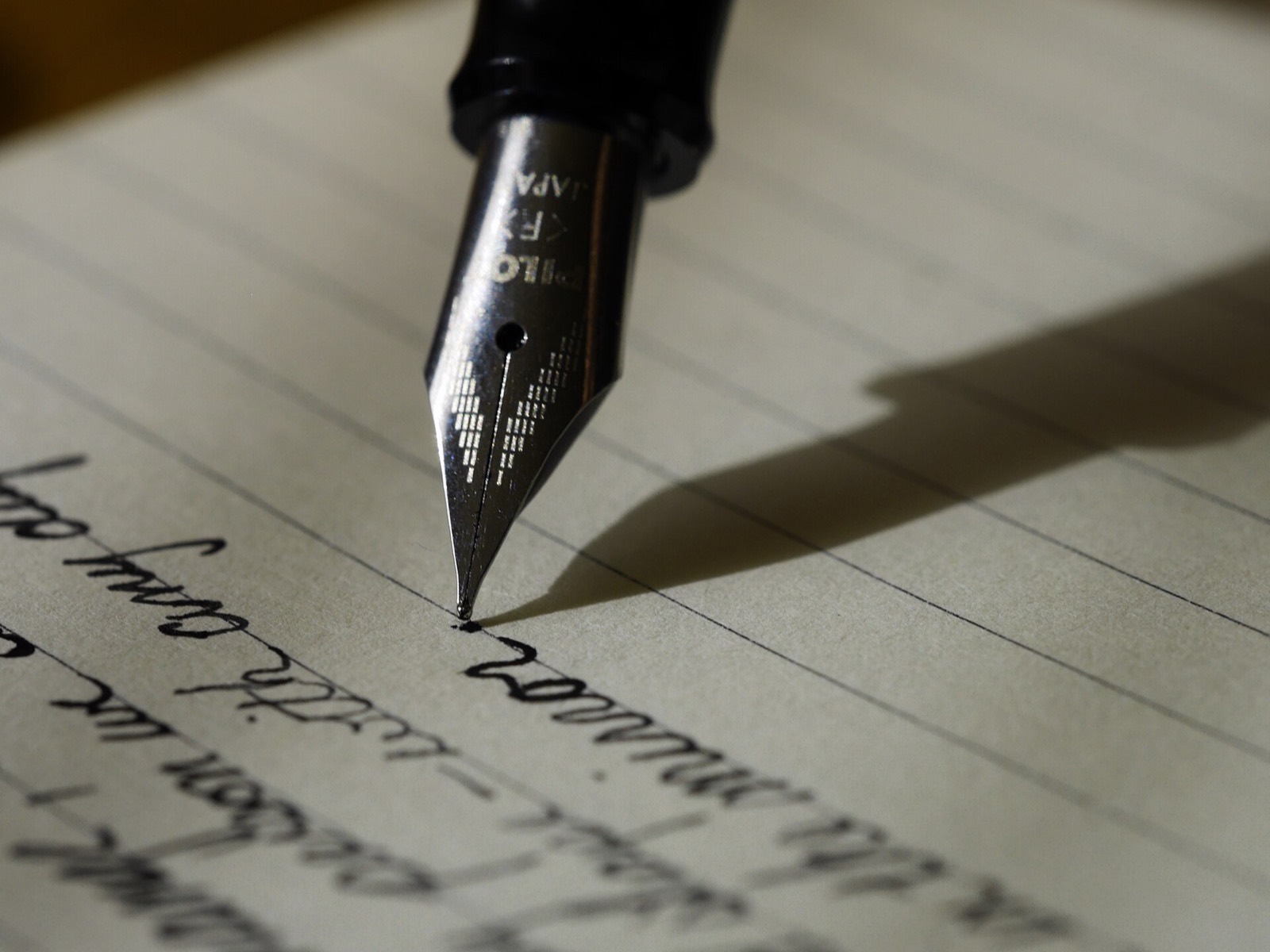 Il pennino di una stilografica che scrive su un foglio a righe