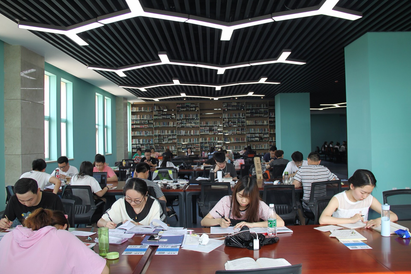 Persone che studiano ai tavoli di una grande biblioteca